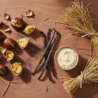 roasted chestnuts, dried hay, creamy vanilla in a flatlay on a cedarwood background